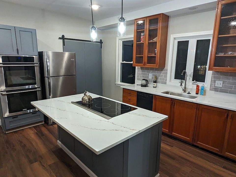 Kitchen with a new induction stove in the center island, new fridge, double oven, and dishwasher.