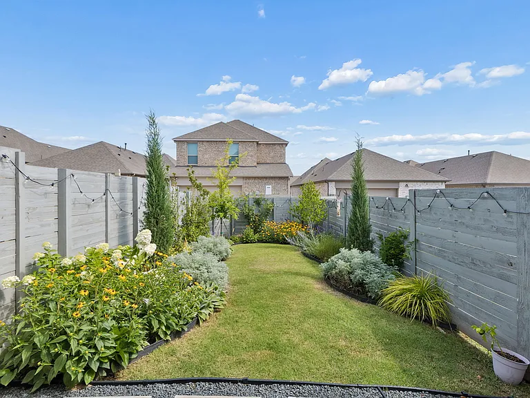 Professionally landscaped, fenced yard with patio lighting and gas grill connection.