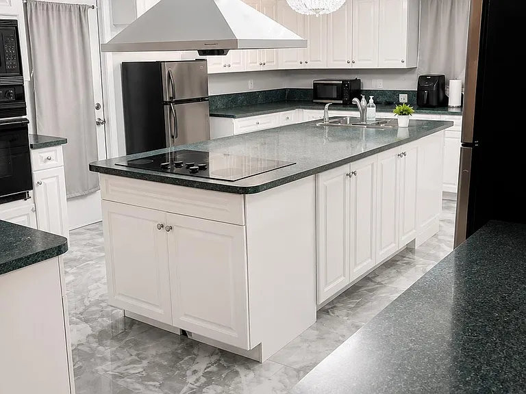 Spacious kitchen with a large island cooktop, ample white cabinetry, and generous counter space for meal prep.