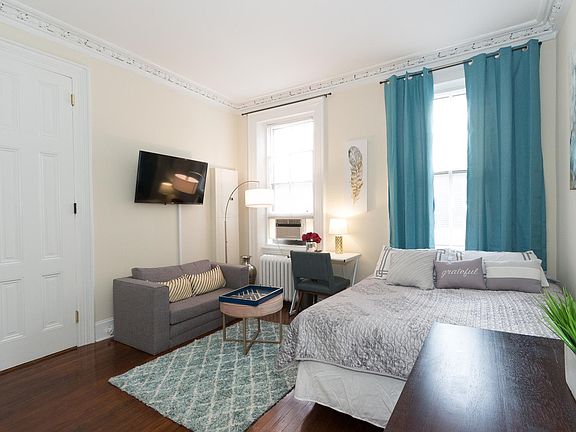 Living space / bedroom with wall mounted tv and sofa, high ceiling