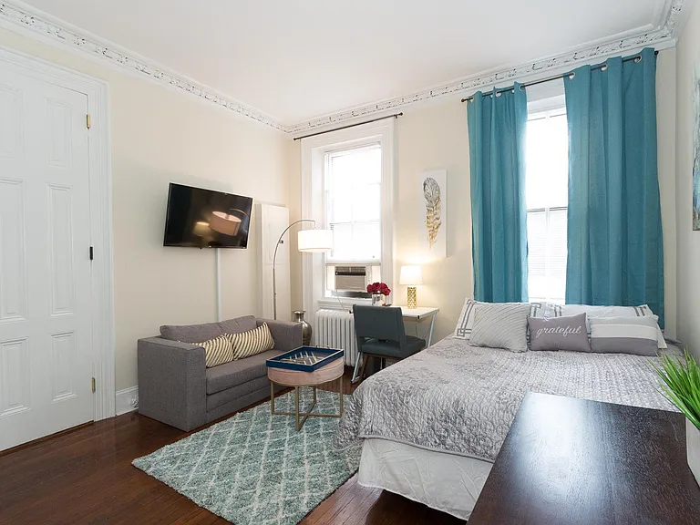 Living space / bedroom with wall mounted tv and sofa, high ceiling