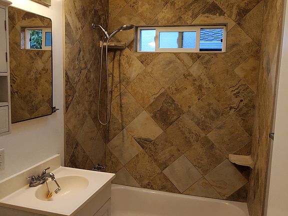 Tile bathroom with tub/shower, window ventilation and skylight.