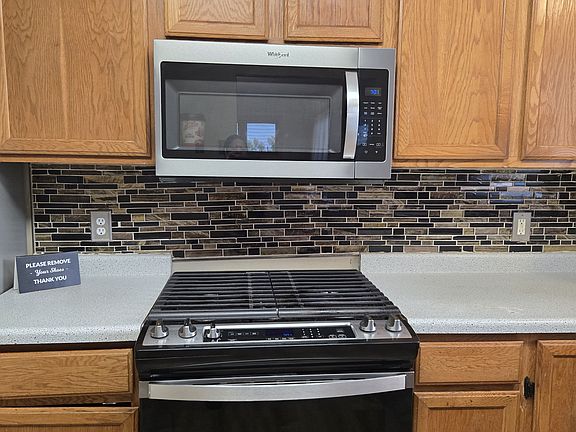 Tiled backsplash with large gas range and microwave
