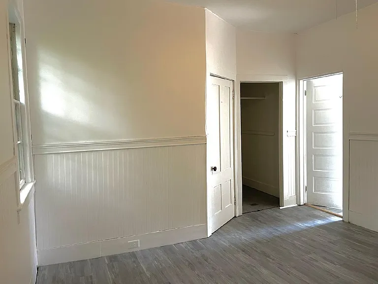 Main Bedroom with Bathroom door on left behind the closed door. Deep closet on the right. Doorway into living room on right.