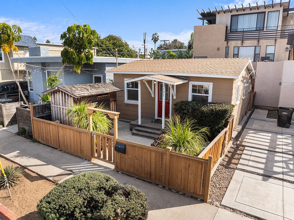 Front of house with enclosed front yard and storage shed. Off-street parking is adjacent on the right side.