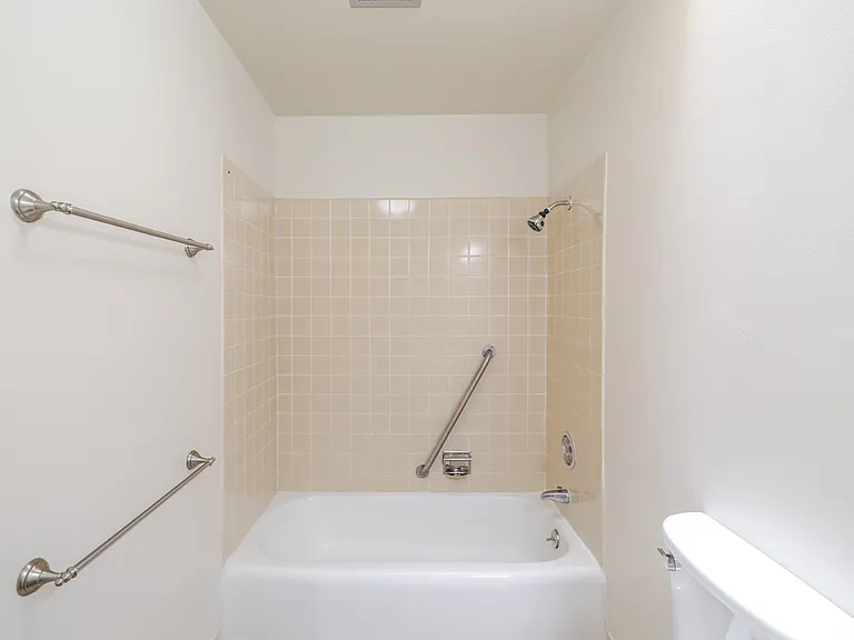 Bathroom A features a clean, functional layout with built-in safety grab bars and a full-size bathtub.