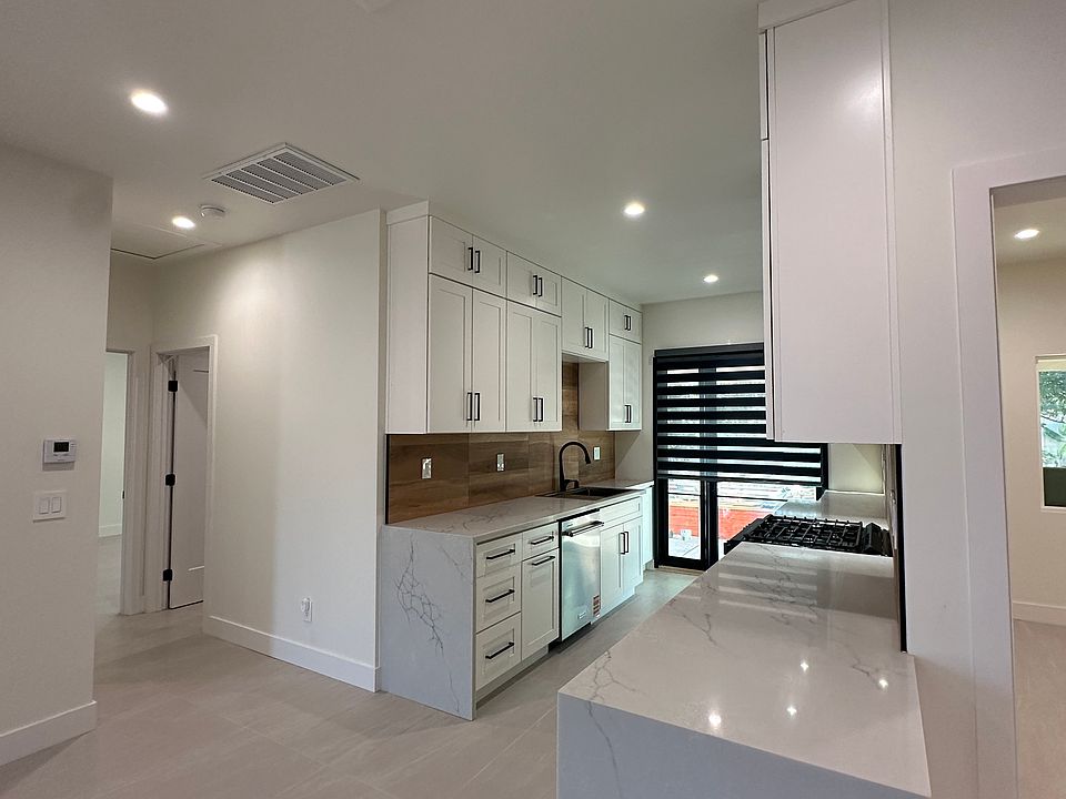 Modern kitchen with sleek cabinetry, quartz countertops, stainless steel appliances, and built-in dishwasher. Open layout flows into the living area, with recessed lighting and ample storage_perfect for cooking and entertaining.