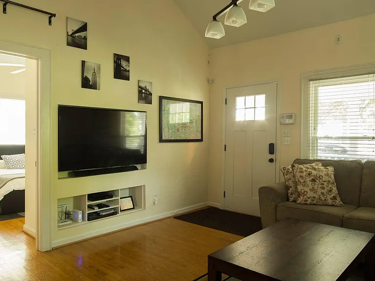 Front door and living room, built ins for TV, internet, etc. with view into the second bedroom.