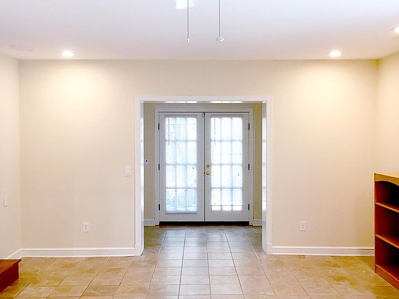 Living room with high ceilings, fan & french doors providing lots of light.