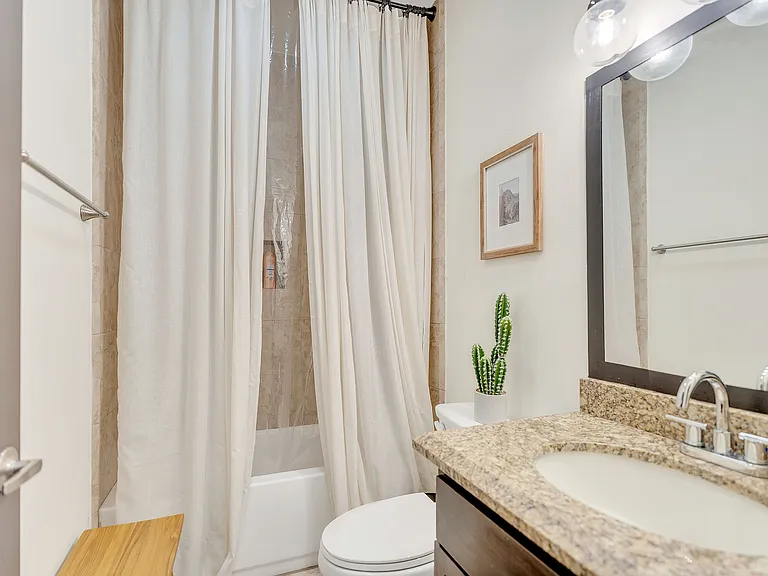 Interior view of a bathroom at La Joya Apartments, Laredo, Texas, showcasing a shower, toilet, and sink