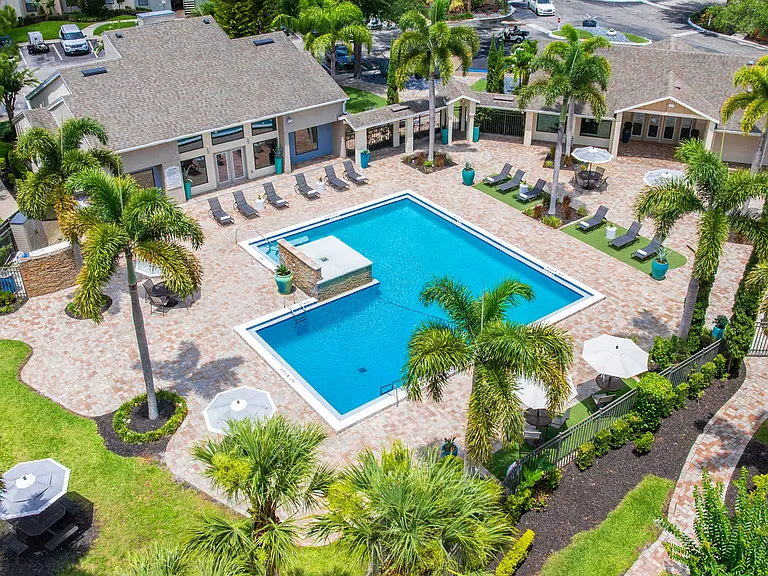 Enjoy the ultimate Florida lifestyle with our beautifully landscaped pool area featuring poolside loungers and umbrella-shaded seating areas.