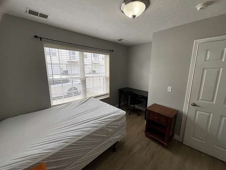 Ground floor bedroom furnished with two side firm pillow top mattress, desk with chair, nightstand and dresser.