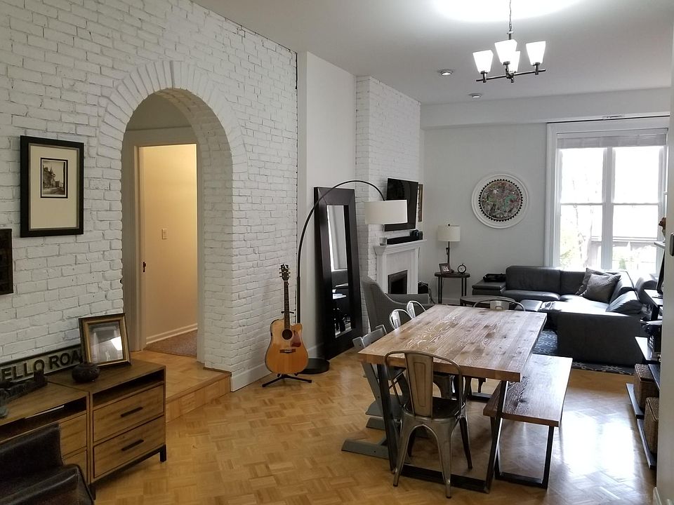 Large, open floor plan den, dining room and living room with exposed brick and a wood-burning fireplace. Great for entertaining with plenty of space for an 8-person dining room table, wrap-around couch and sitting chairs.