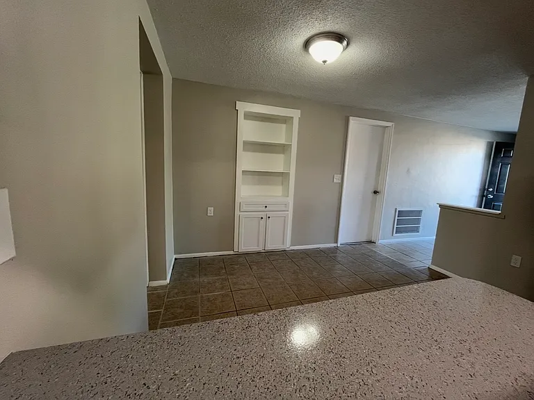 View from standing in the kitchen looking at where a table and chairs might go. Built in cabinet adds a nice touch and the door leads into the garage.