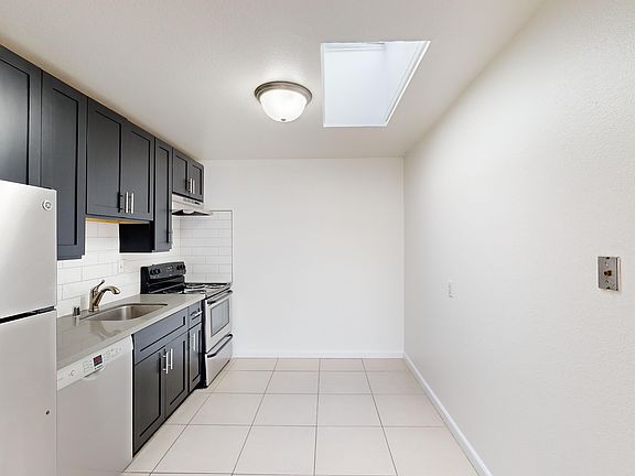Kitchen with cabinets, refrigerator, stove, range hood, and sink