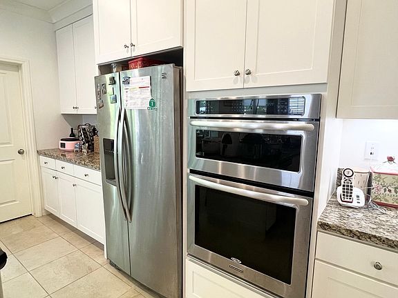 Kitchen with white shaker cabinets, stainless appliances, walk-in pantry and large center island