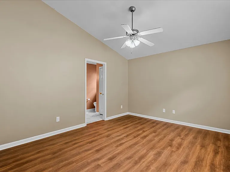 Master bedroom with vaulted ceiling leading to master bath and walk in closet