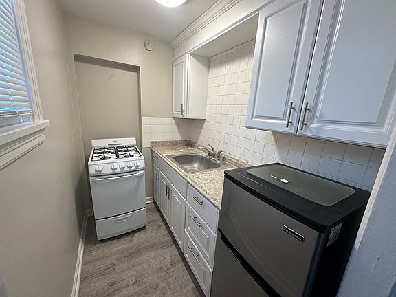 Charming compact kitchen with modern white cabinetry, sleek countertops, and cozy appliances, perfect for efficient living.