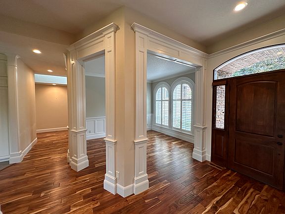 View of main door, dining room, and hallway leading to hallway for three bedrooms and garage entry.