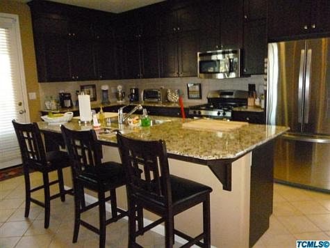 Kitchen has granite counters, tile floors, gas range