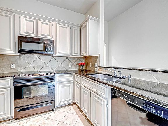 Beautifully painted cabinets in the kitchen with neutral tile and granite counters.