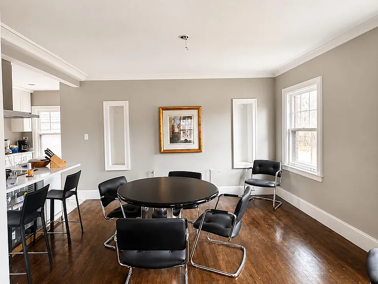 Dedicated dining area with a round table, hardwood floors, and a large window, open to the kitchen for easy entertaining.
