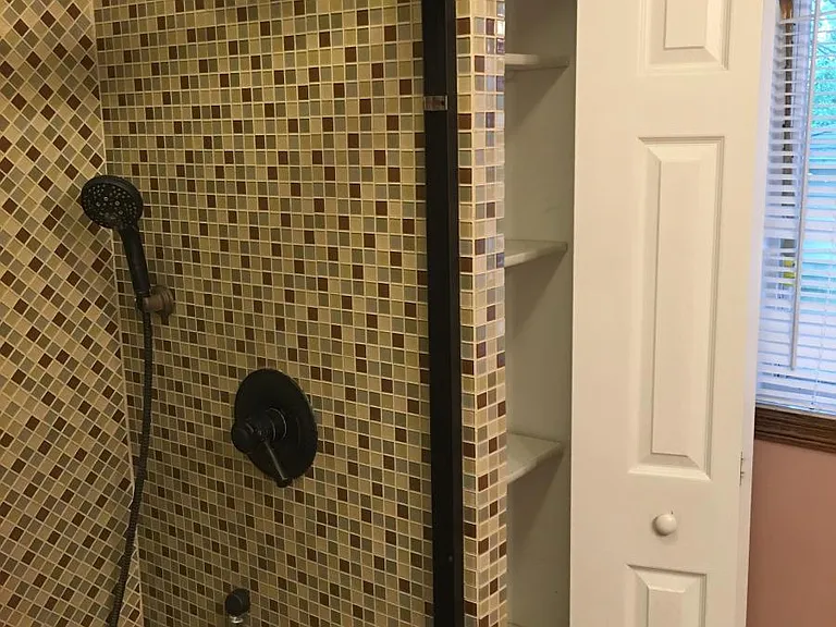First floor bathroom with custom tile work and built in closet area.