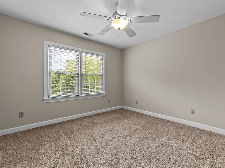 Secondary bedroom with double windows, ceiling fan, neutral paint, and soft carpet.