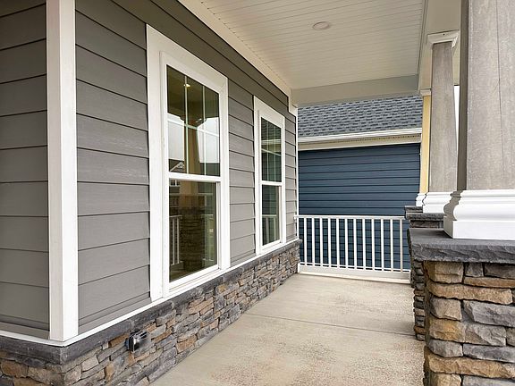 Front Porch with stone kneewall, vinyl siding, and white guard rail