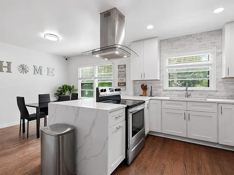 Updated kitchen with generous cabinet storage, stone-look counters, and an island with vent hood beside the dining area.