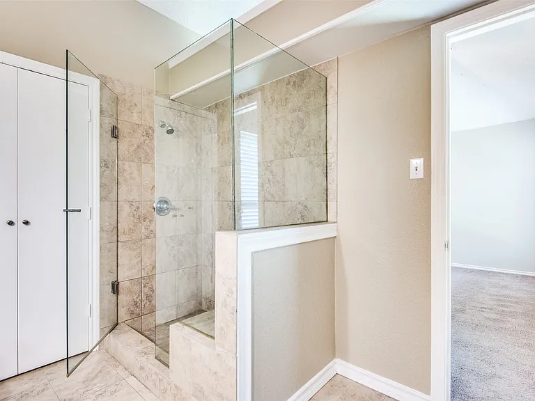 Walk-in shower featuring glass enclosure, tiled walls, and a built-in bench
