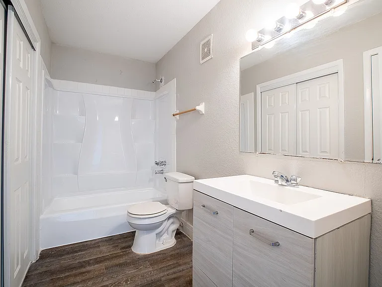Bright and modern bathroom featuring a sleek vanity, elegant mirror lighting, and a pristine bathtub with contemporary design.