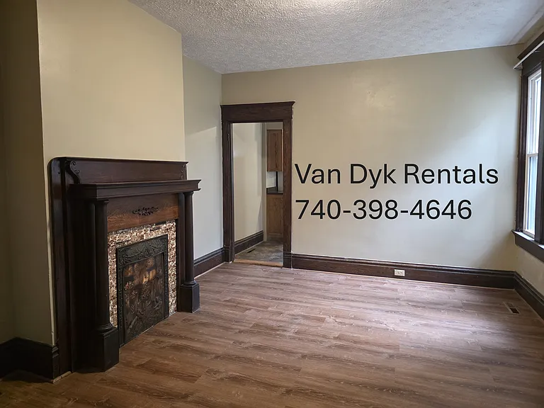 Dining room view of decorative fireplace and doorway into kitchen.