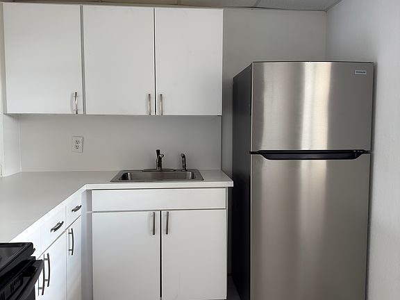 Full kitchen with all new appliances and countertops. An arch overlooking the living room with seating.