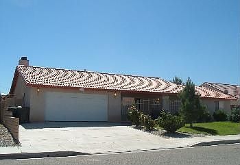 Front of home with extended Driveway and Stone fencing-mature trees/roses