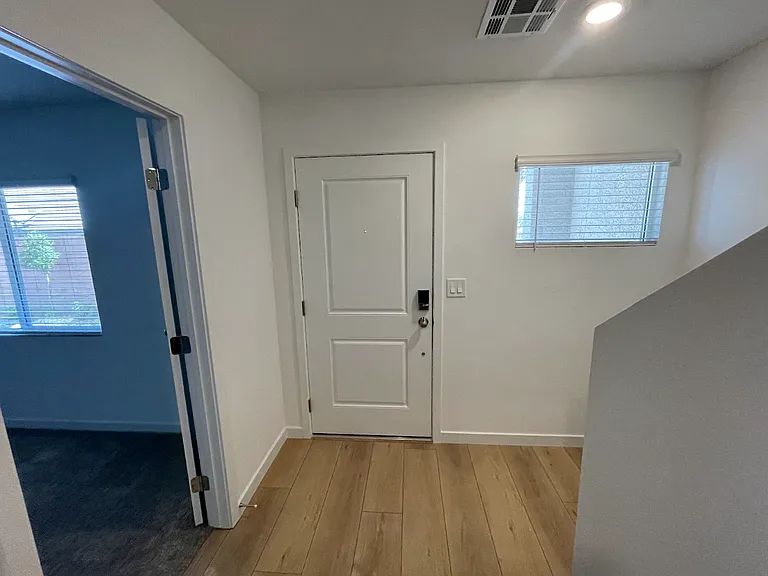 Front door/entry way from garage door behind. Bedroom on left