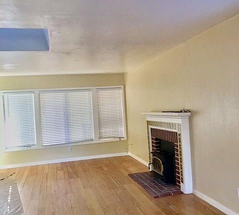 Refinished original wood floors, this is the living room area with a wood stove. New central heat and AC was added to both buildings. You can see the large skylight that bring light deep into the living/dining room areas.