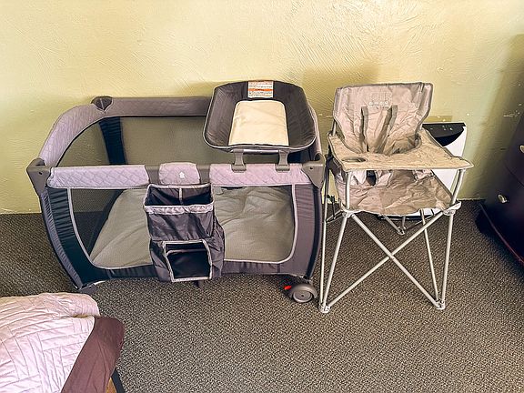 Pack n play and portable high chair in bedroom.