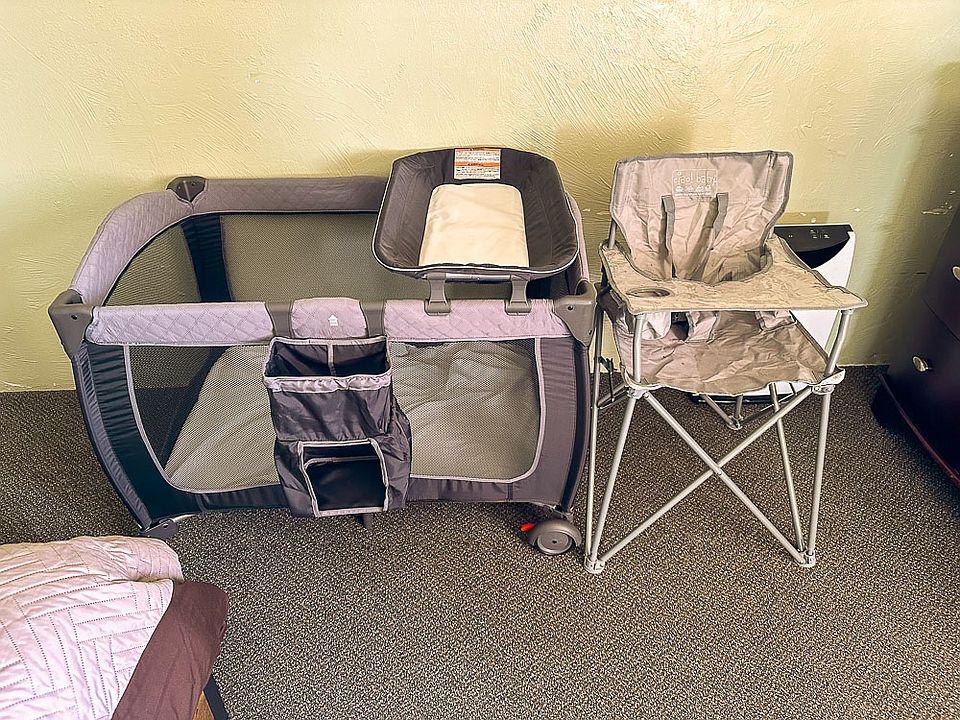 Pack n play and portable high chair in bedroom.