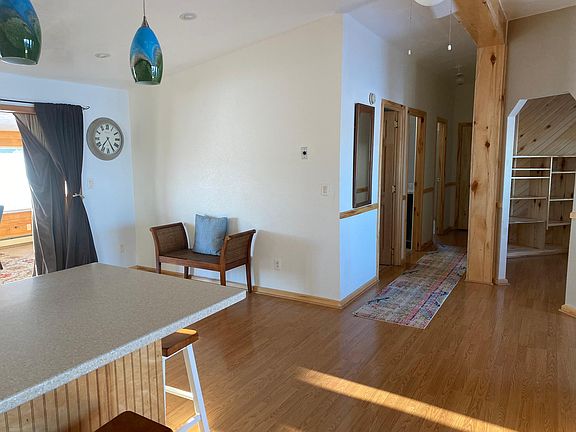 Living room looking to kitchen counter, sunroom and hallway to den, 2 bedrooms, laundry room, bathroom.