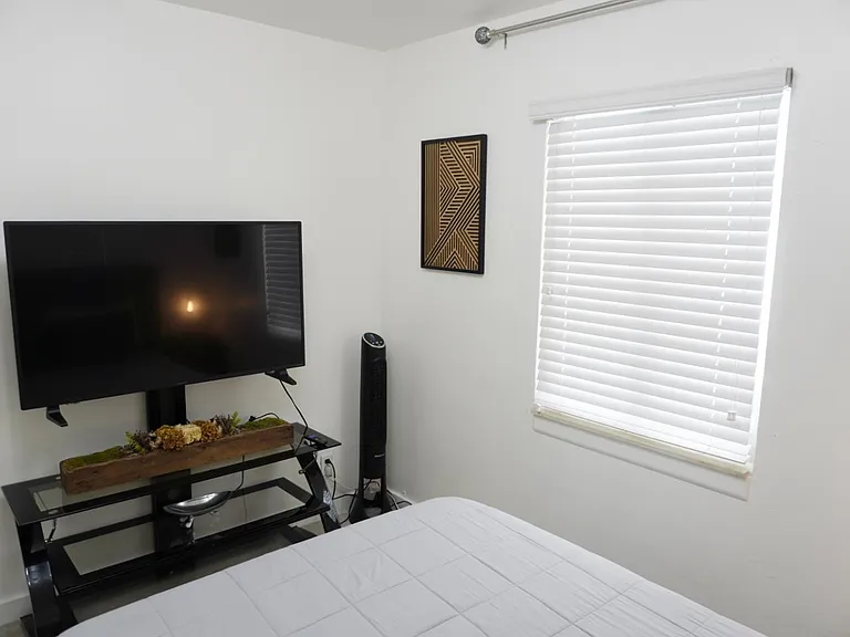 Private bedroom with a window and blinds, plus a TV setupideal for relaxing and streaming after a long day.