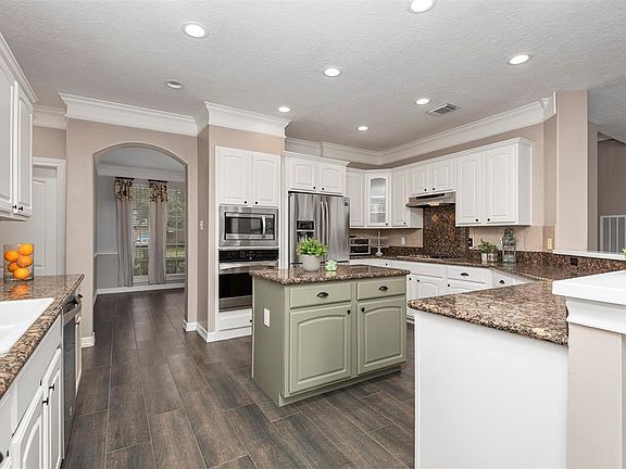 The elegant kitchen has it all. The gorgeous wood look tile is easy care and the white and contracting color cabinets offer so much space. A walk-in pantry offers ample storage, and the breakfast bar adds seating for plenty of guests. This is the kit