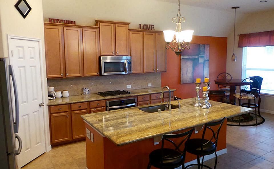 Huge island kitchen with unique granite counters and light fixtures