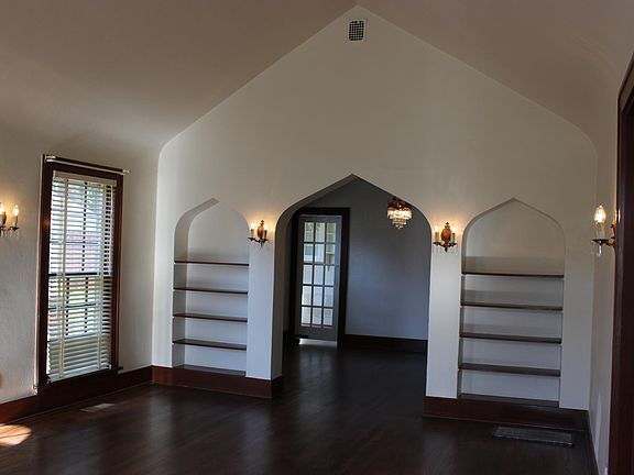 Large livingroom with vaulted ceilings and original sconces.