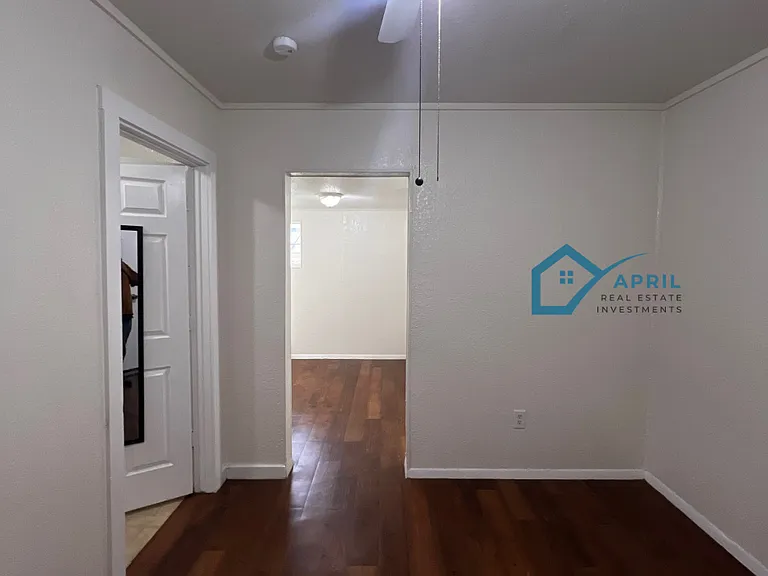 View from the front door into the living room and the kitchen beyond. Bathroom is to the left.