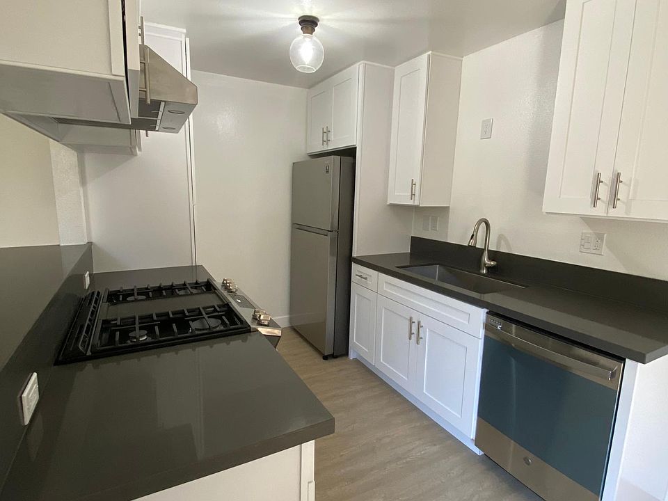 White kitchen cabinets with gray quartz countertops and stainless steel appliances.