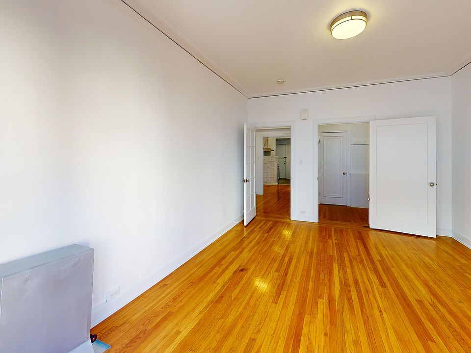 Bright, minimalist room with hardwood flooring, and open closet doors leading to another space.