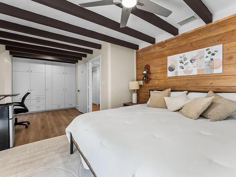 Spacious bedroom with a ceiling fan, large wardrobe storage, and a dedicated desk area for working from home.