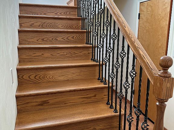 Entry Hallway with Wrought Iron Staircase. Garage entry seen at right. Additional Storage area Underneath.