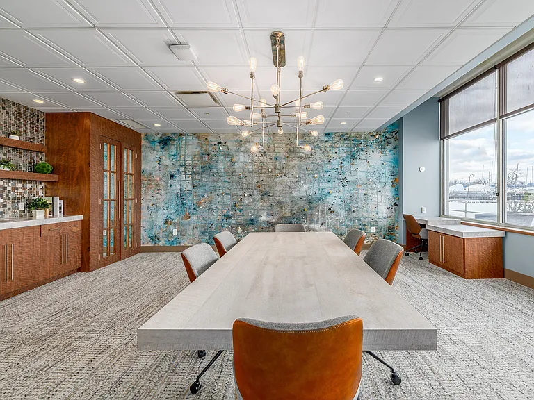 Meeting room with modern chandelier, abstract wall art, and large window offering a scenic view.
